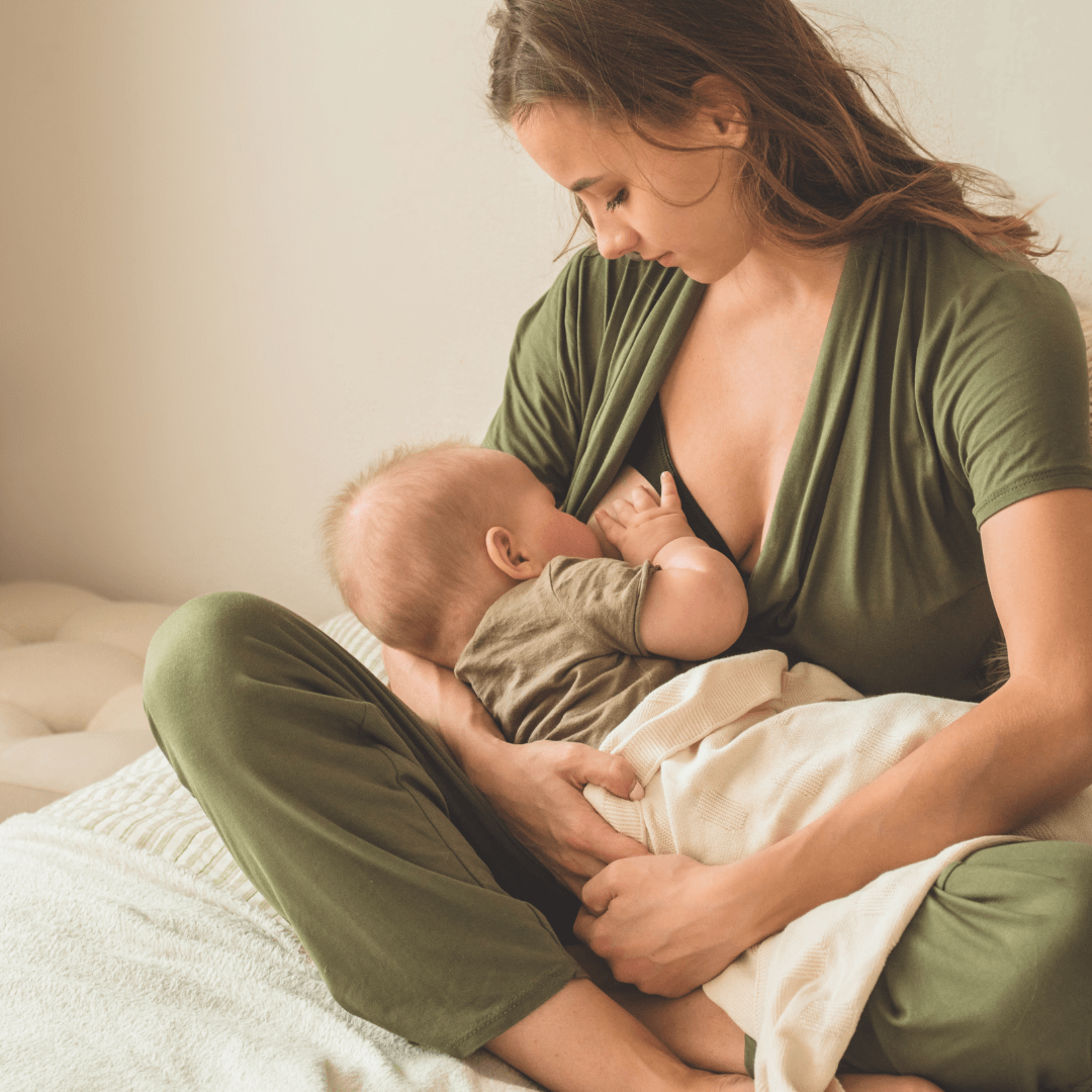 Zu sehen ist eine Mutter, die ihr Baby stillt, im Sitzen auf dem Schoß.