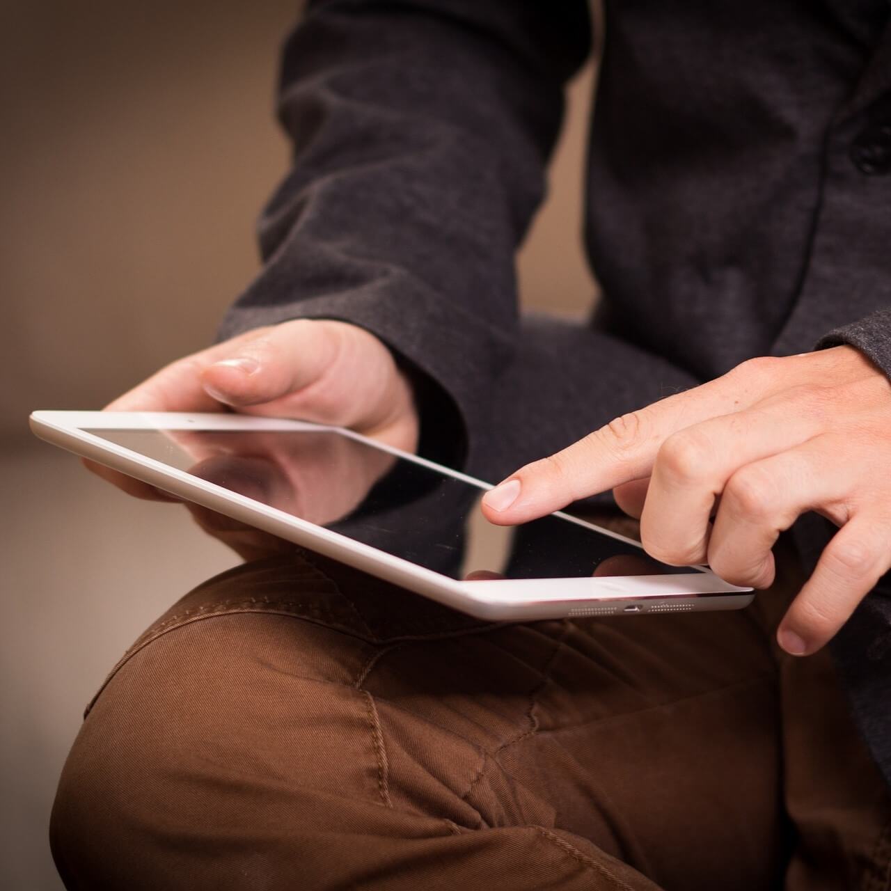 Zu sehen sind zwei Hände einer Person, die auf einem Tablet tippen.